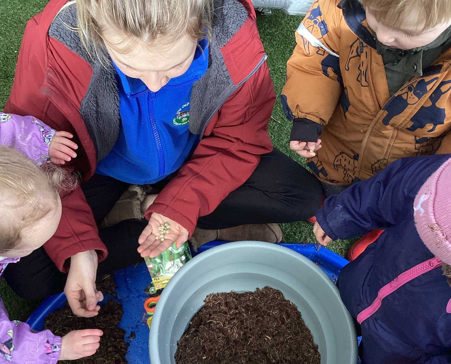 A woman and three children are playing in a bucket.